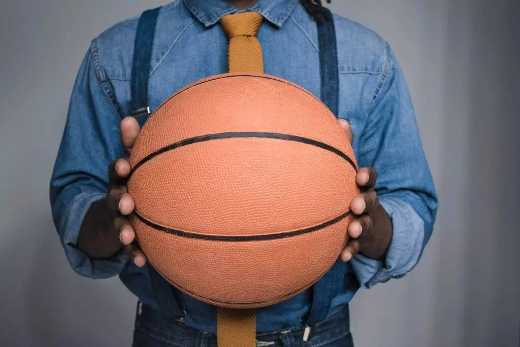An attorney in Lakeland, donning a denim shirt and yellow tie, confidently holds a basketball with both hands.